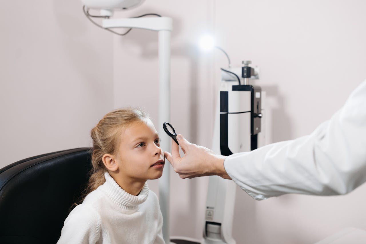 Caucasian girl undergoing an eye exam by a professional in a clinical setting.