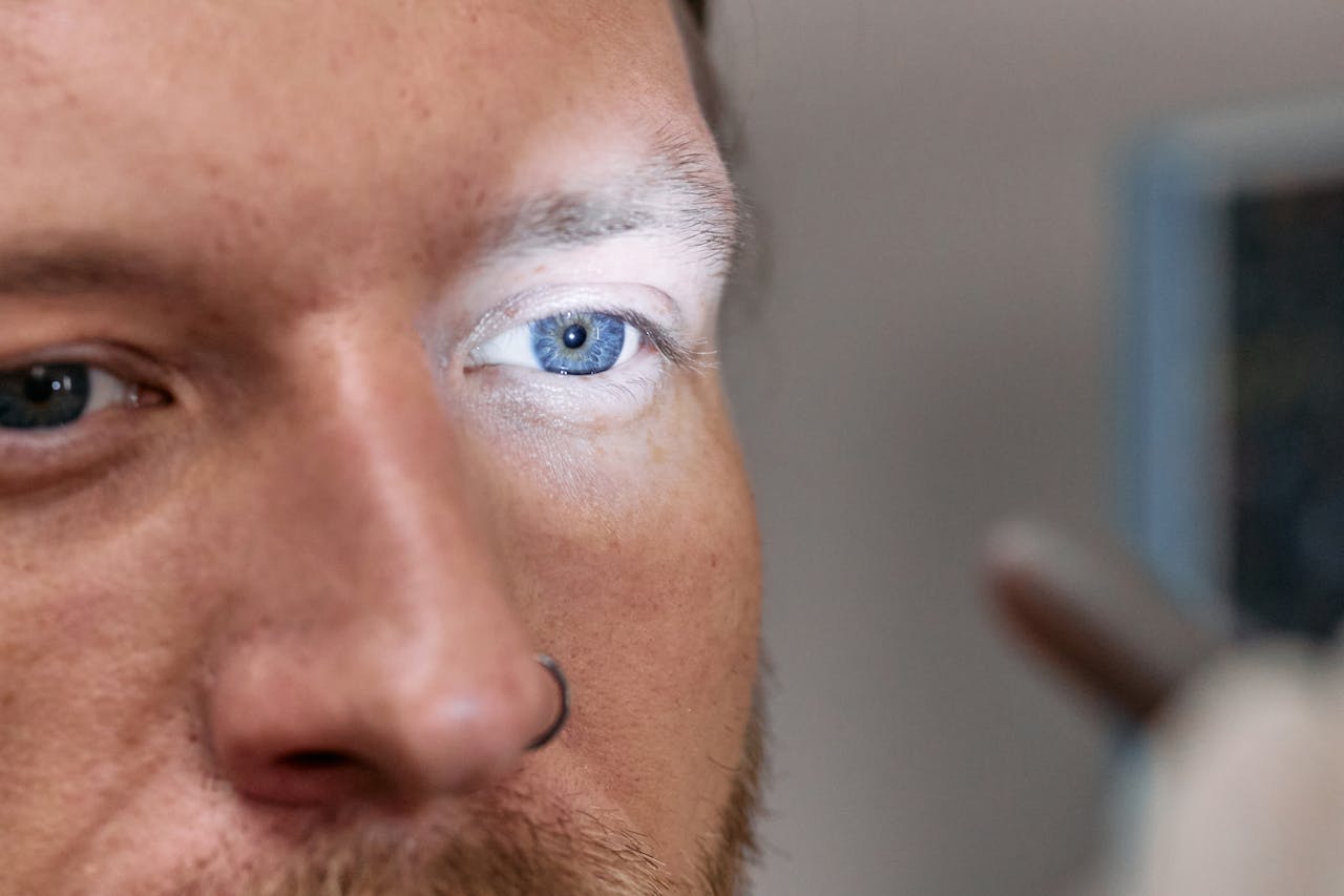 A close-up view of a mans blue eye under examination light by an ophthalmologist.